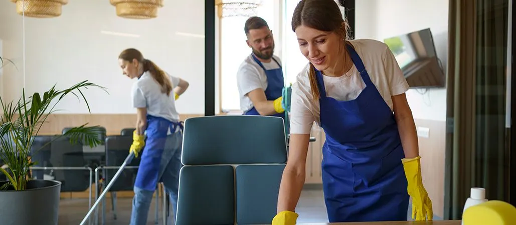 Két takarító egy modern irodában, felmosás és asztaltörlés